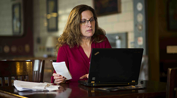 An accountant sitting in her business going over receipts from the day at her laptop