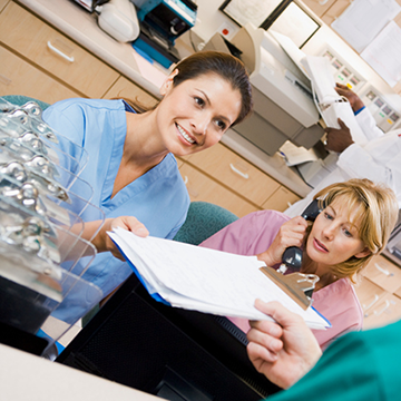 A medical office professional handing documents over to a patient