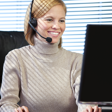 A business professional talking on a headset while looking at computer