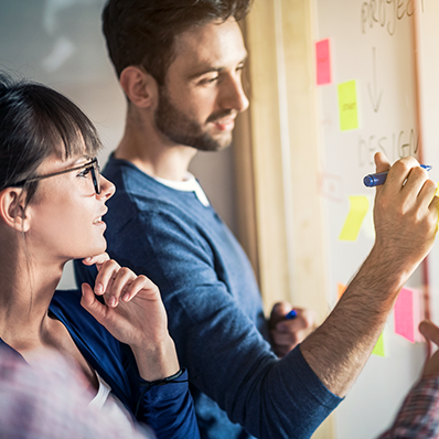 Two business professionals brainstorming with a marker board and post-it notes