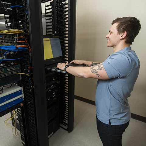 An IT - Cybersecurity Specialist student working hands-on with classroom technology