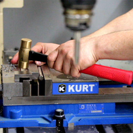 Close up of a hand using a hammer to crush metal pieces