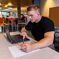 A student sitting in a table booth and studying with a laptop