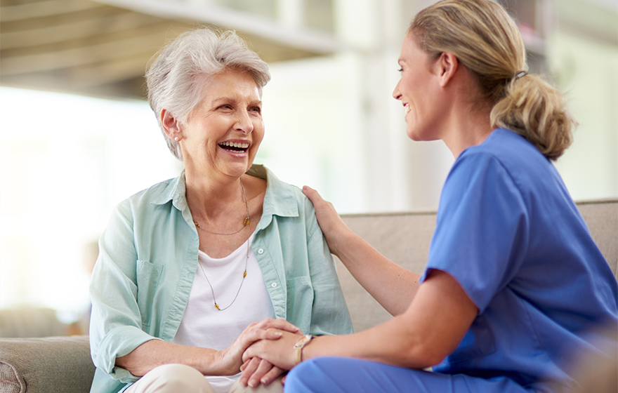 caregiver sitting with smiling elderly woman