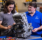 A student working on a small engine with instructor supervision in the power sports lab on campus