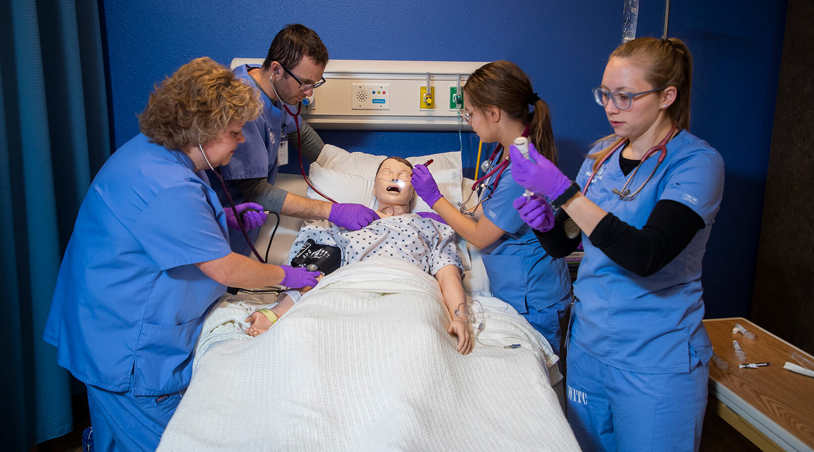 A group of students working together and checking vitals on a simulated patient