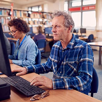 An older adult student working at a computer