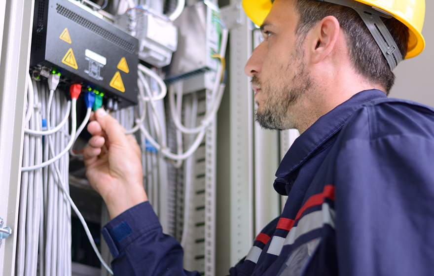 Broadband technician checking cable on electrical panel