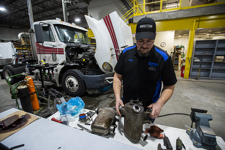 A diesel repair technician analyzing parts in a shop