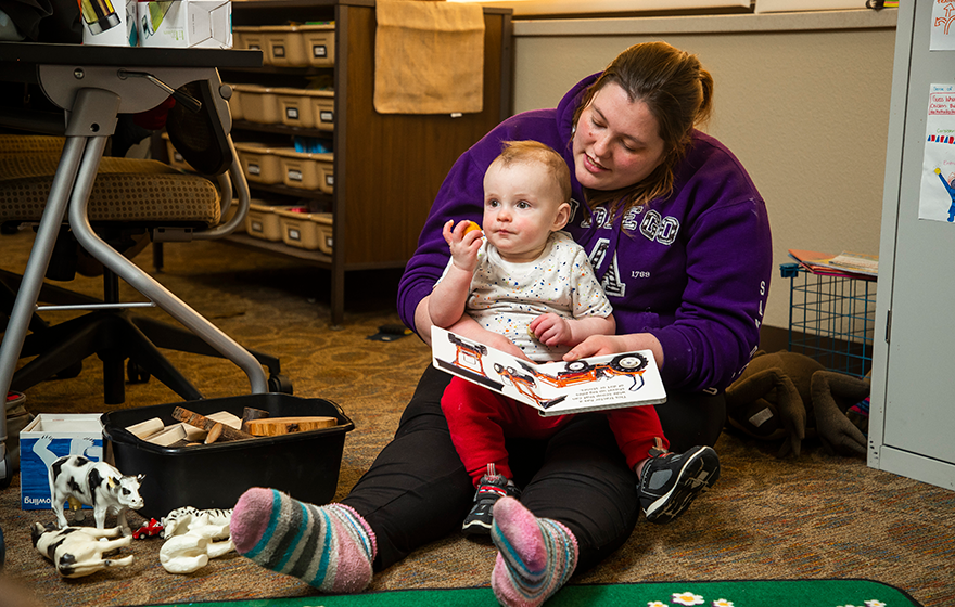 A student reading a book to a baby