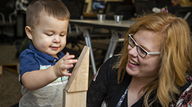 An Early Childhood Education student and a toddler playing with blocks