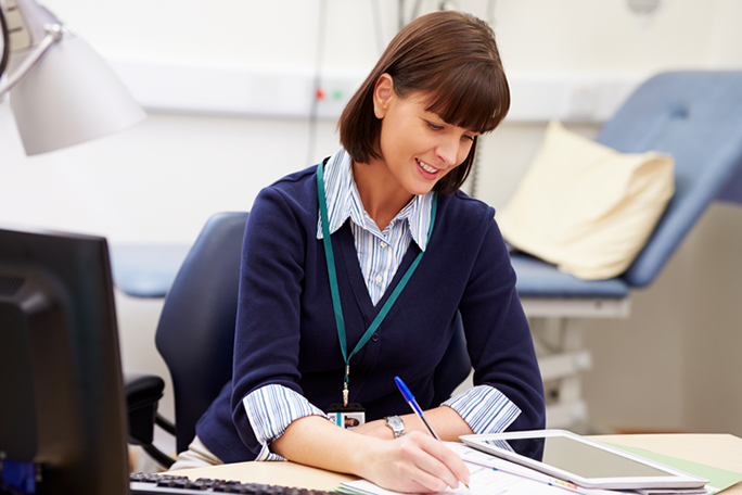 A medical office professional sitting at a desk in a doctor's office