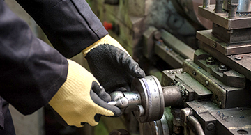 A worker in protective gloves using a machine