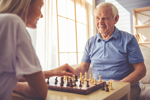 A caregiver playing chess with an aging adult