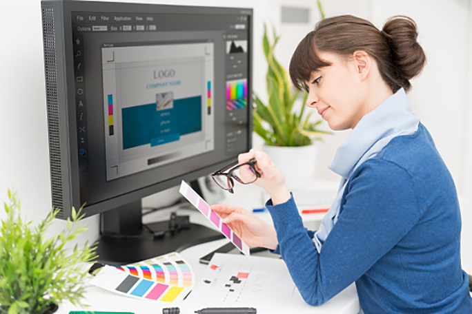 A graphic designer looking at color samples at a computer