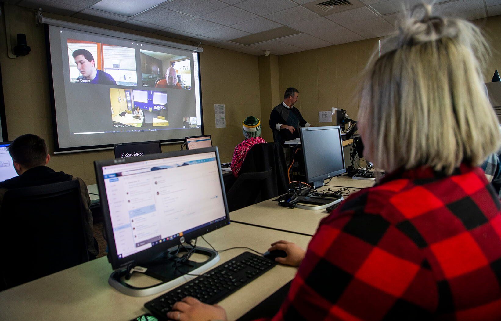 Student in a classroom with other students attending virtually