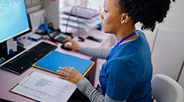 A medical administrative professional looking at a computer taking a phone call