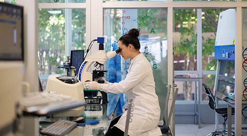 Female looking into a microscope inside of a lab