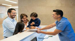 A medical office professional greeting a FAMILY at a front desk