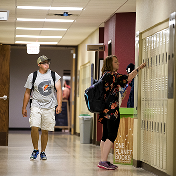 Student walking down hallway and another looking in a locker