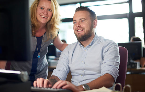 Students at a computer listening to an instructor 