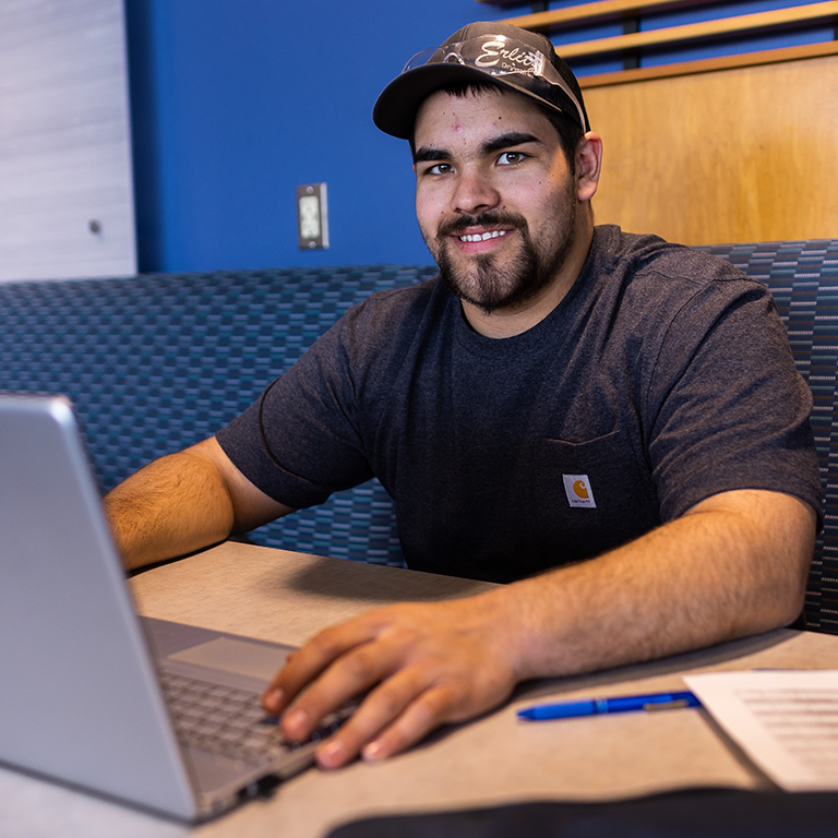 Male student working on a laptop in the New Richmond student lounge