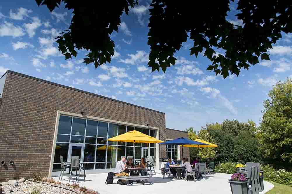 Students sitting outside campus in a patio area