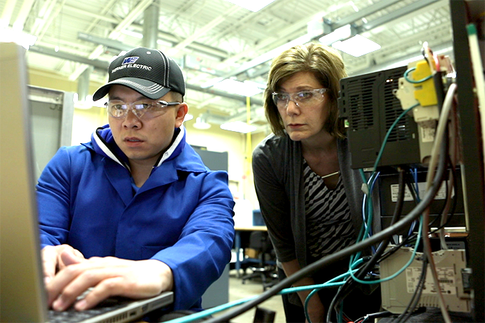 A student working on a computer and the instructor watching