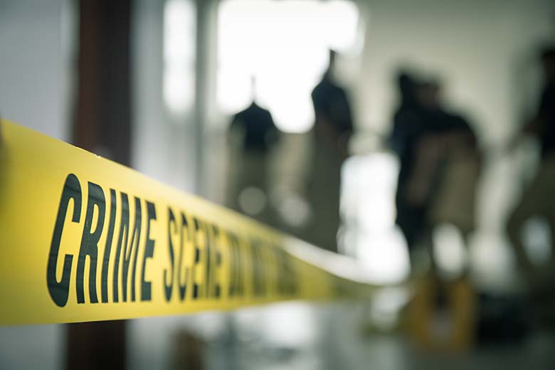 Yellow crime scene tape with blurred images of people in the background