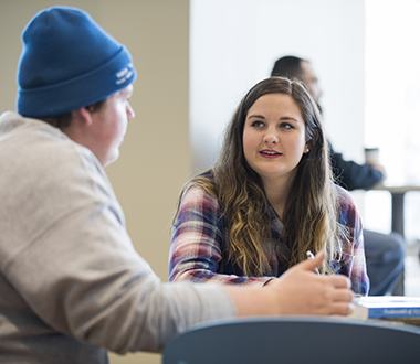 Two students converse in the student lounge