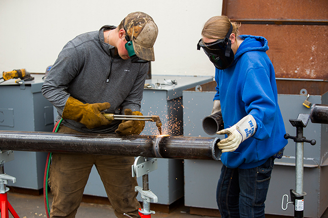 Students welding a pipe