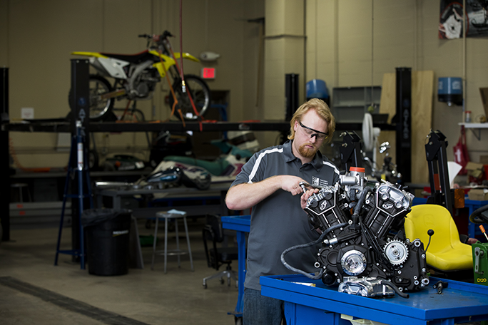 A student working on a motorcycle in the power sports lab on campus