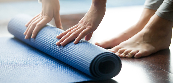 Woman roles out a blue yoga mat