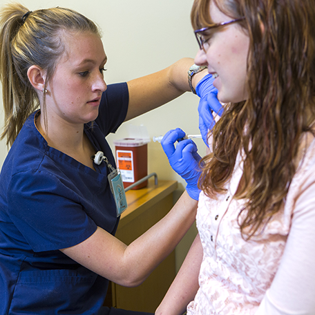A medical assistant student giving a flu shot to a student