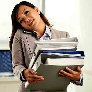 An administrative professional multi-tasking, talking on phone while carrying large stack of books