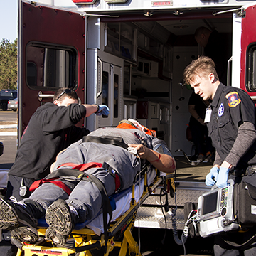 Students loading a stretcher into an ambulance