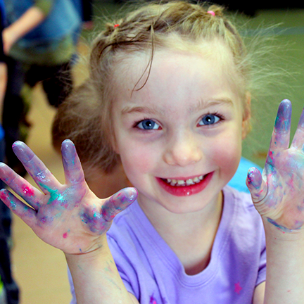 Toddler smiling and holding up messy and sparkly hands