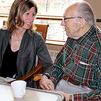 A caregiver at a CBRF sitting at a table with a resident