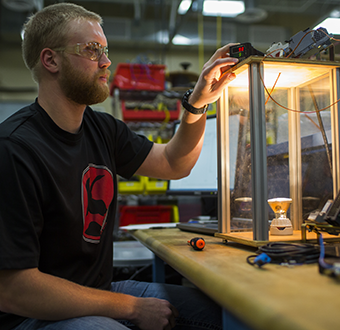 Man works on a project in automation Man works on a project in automation, his face is illuminated by a light bulb