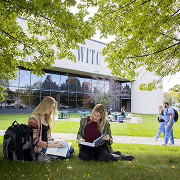 Students studying in the lawn under at tree in front of the Northwood Tech campus