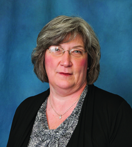 Head shot image of Carol Kraft wearing a patterned blouse with a black cardigan