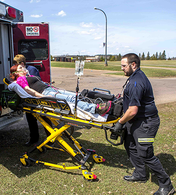Two Advanced EMT students practicing loading a stretcher into an ambulance