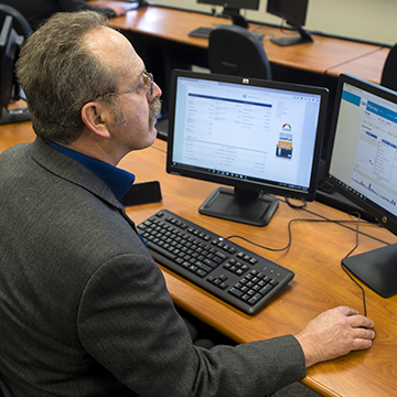 Financial Services student wearing a business suit and checking Internet for stock updates