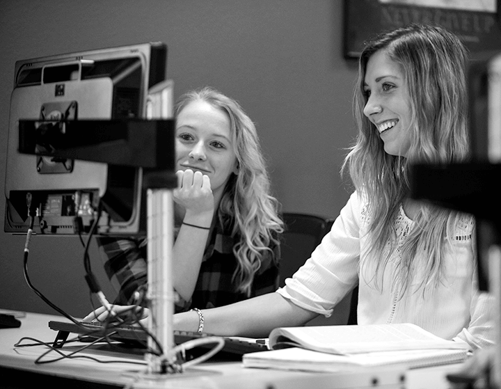 Two students looking at a computer and smiling