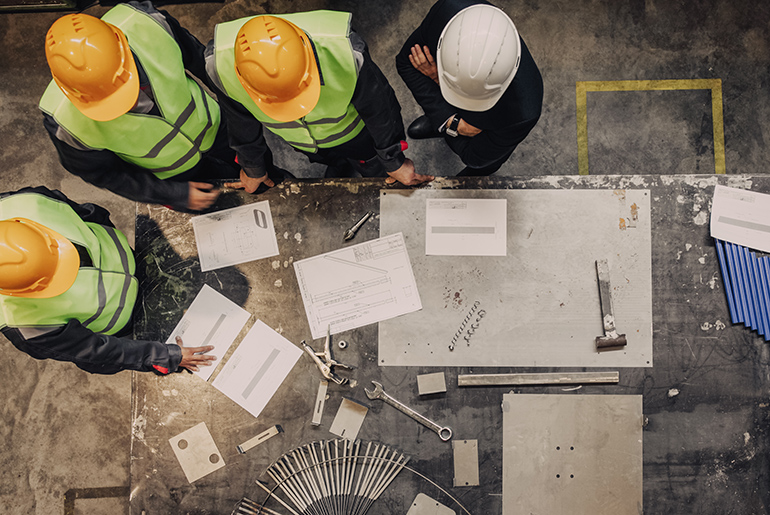 birdseye view of construction workers in hard hats at a safety meeting