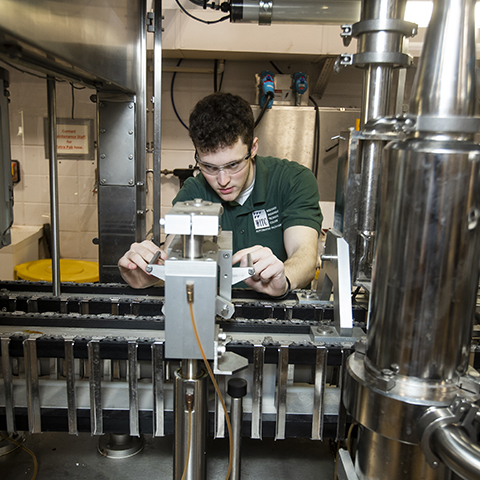An automated packaging student working with equipment in the lab