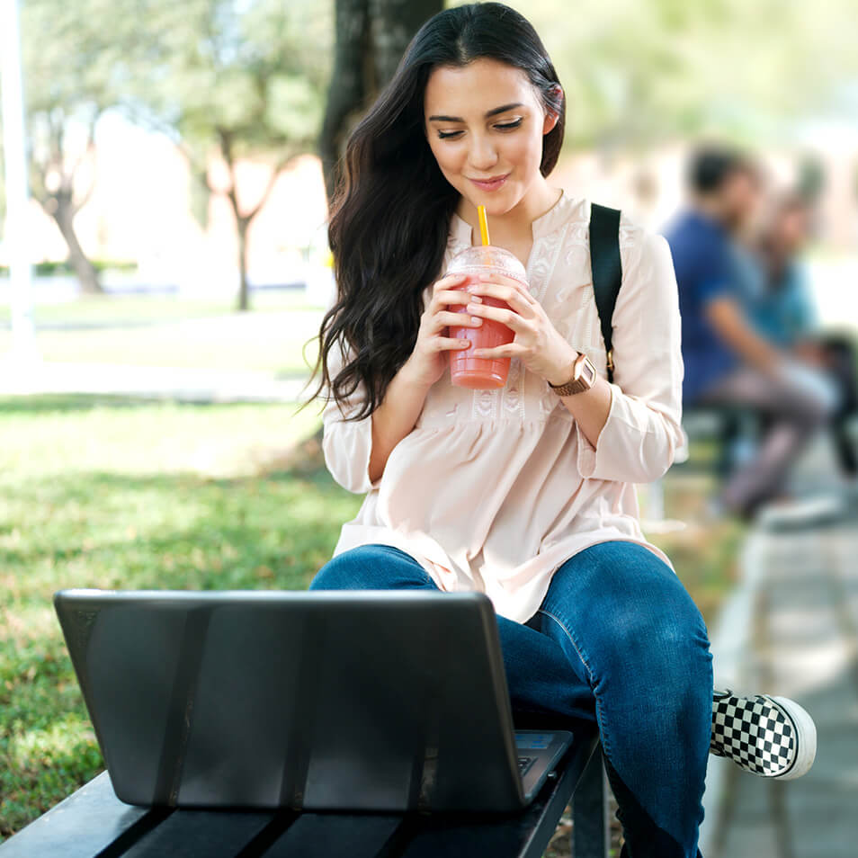 A student sitting outside and doing schoolwork with a laptop