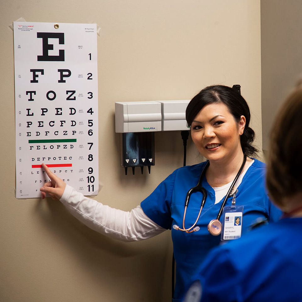 A medical assistant student pointing to an eye chart