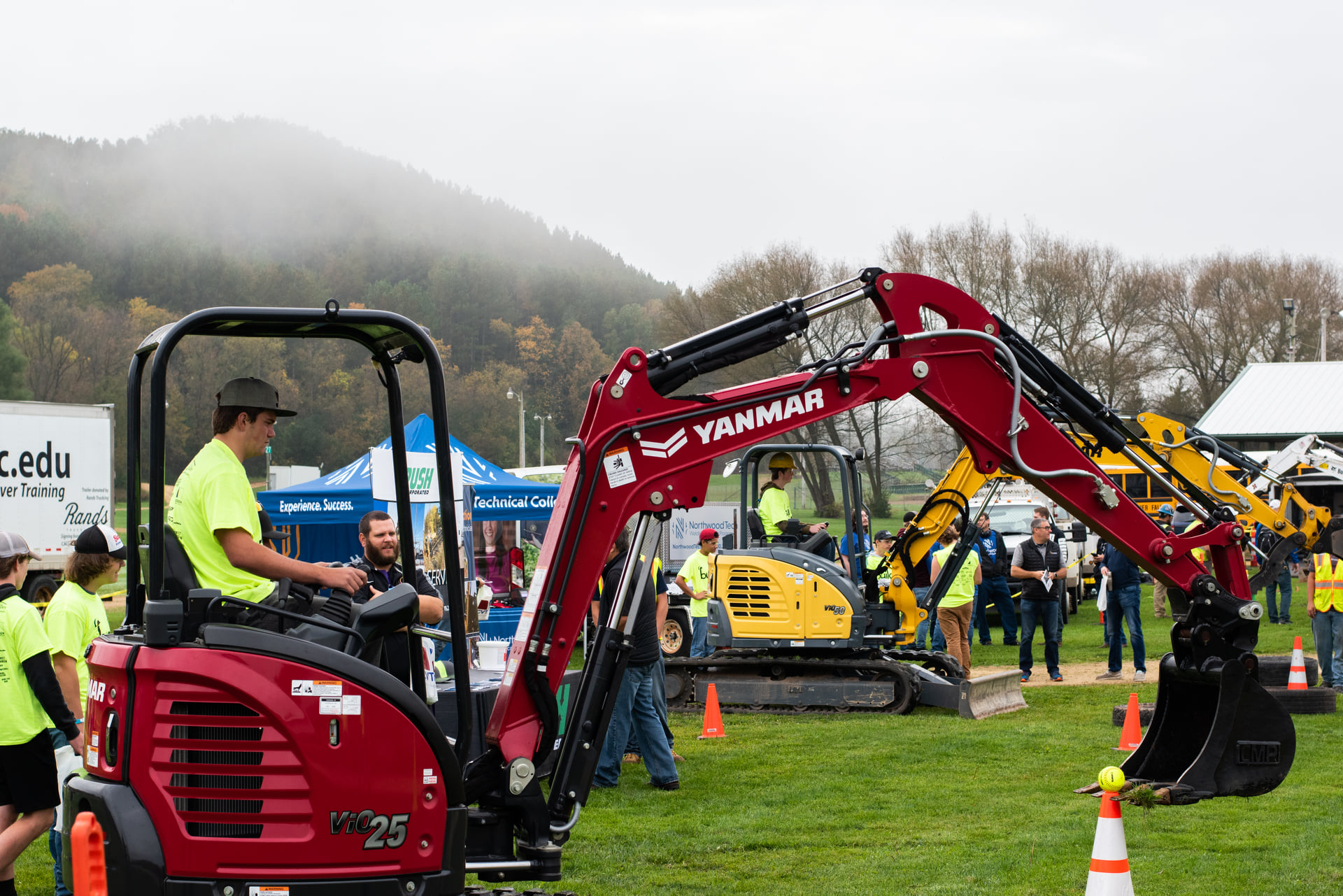 student using backhoe to pluck a softball from an orange cone