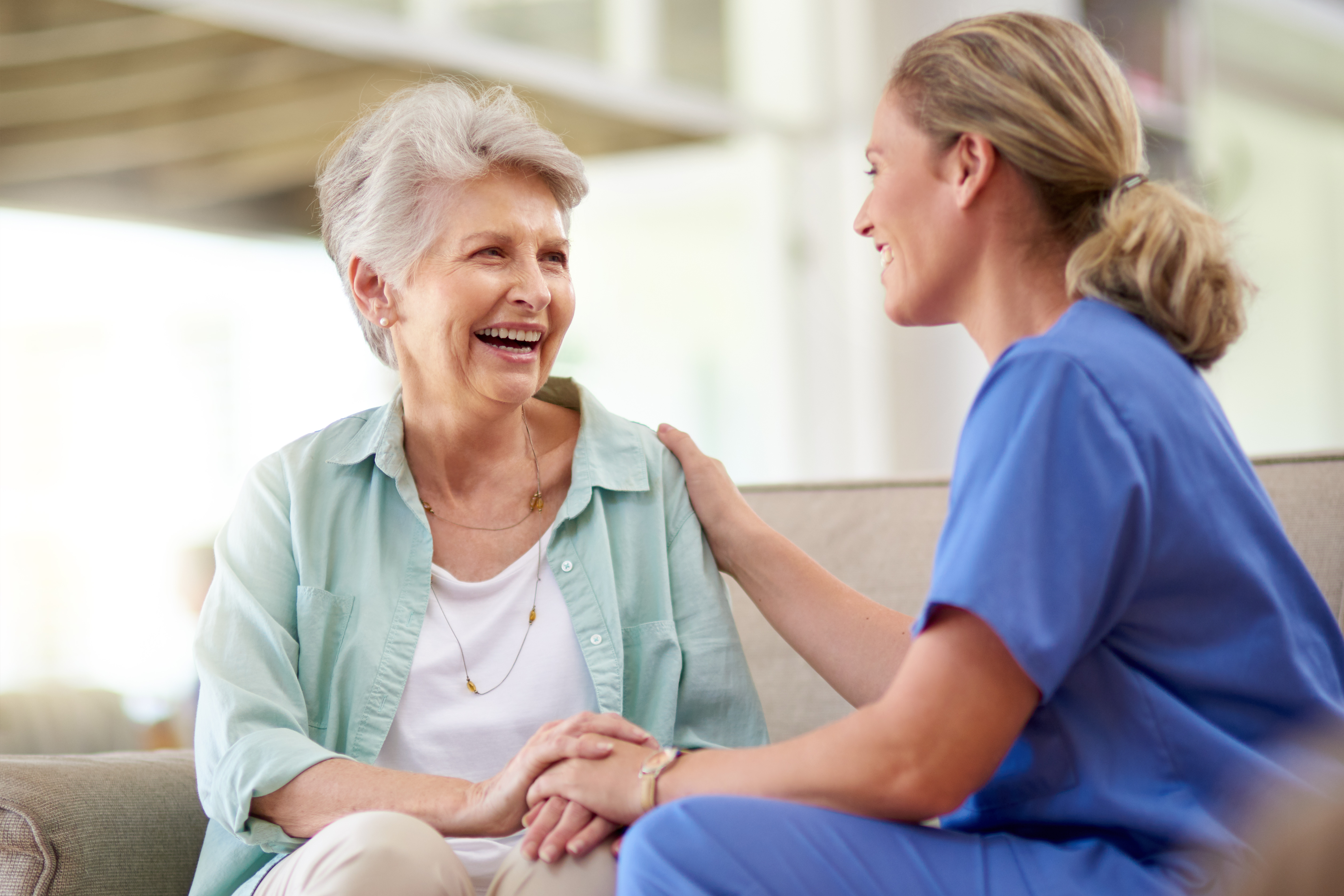 Caregiver sitting with smiling elderly woman